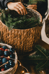 A person's hand placing wreaths in a wicker basket.