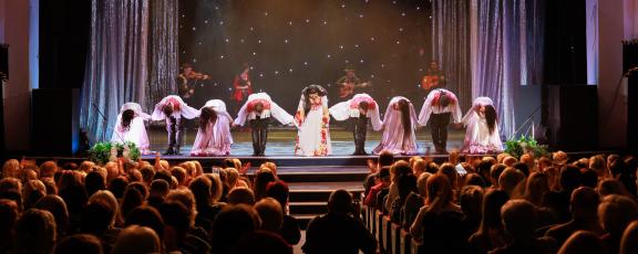 A group of people lined up on stage taking a bow in front of an audience.