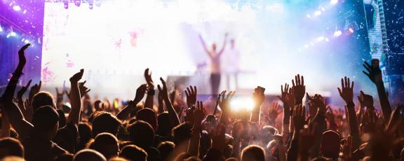 An audience with their arms lifted towards a performer on stage.