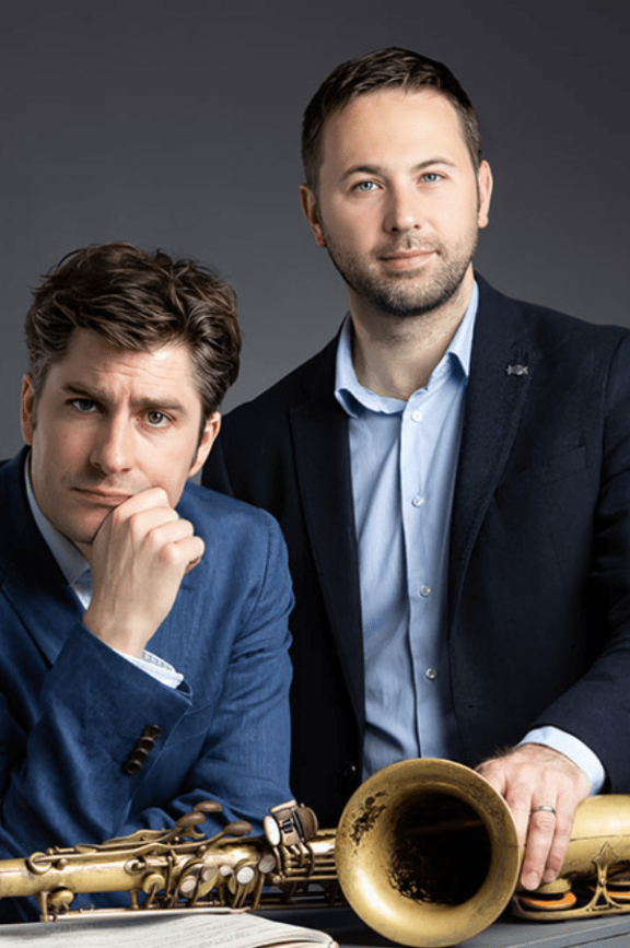 an image of 2 men with a saxophone on the table in front of them