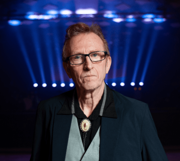 Bruce Watson stands in front of blue stage lights