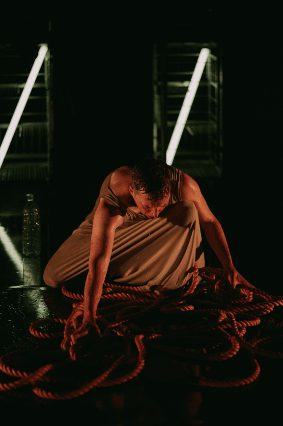 a man sits above a pile of ropes