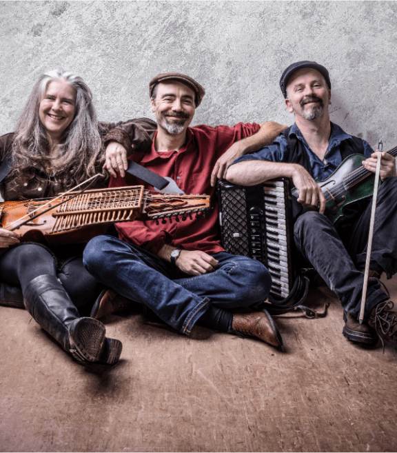 3 musicians sit on the floor with their instruments
