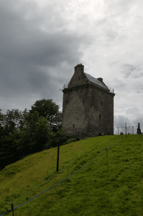 Gilnockie Tower stands on the grass with an overcast grey sky