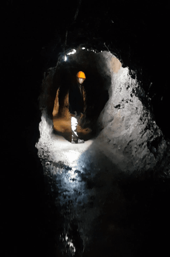 a minor stands in a dark tunnel