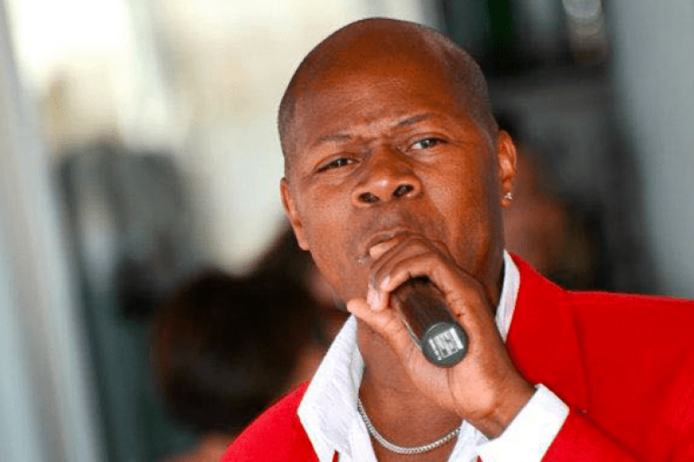 A man in a red suit singing in a microphone.