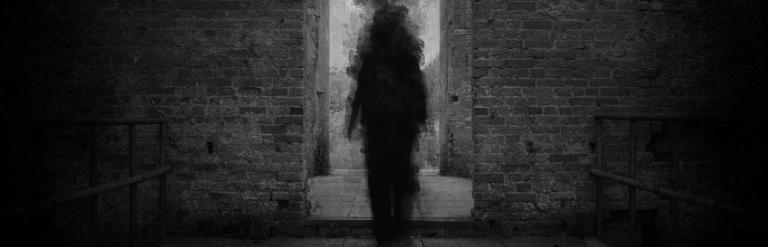 A darken doorway with a silhouette of a person going through it.